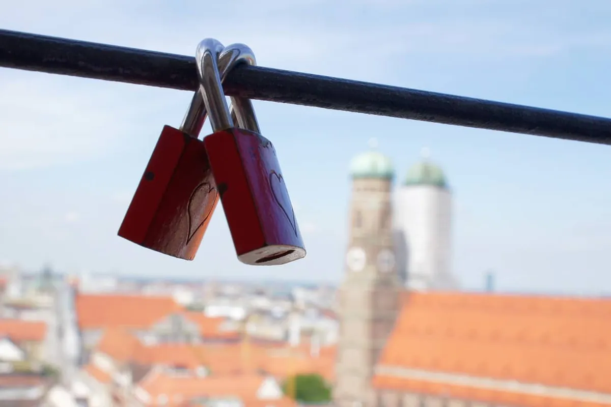 Liebesschlösser an einem Geländer mit Blick auf die Münchner Frauenkirche