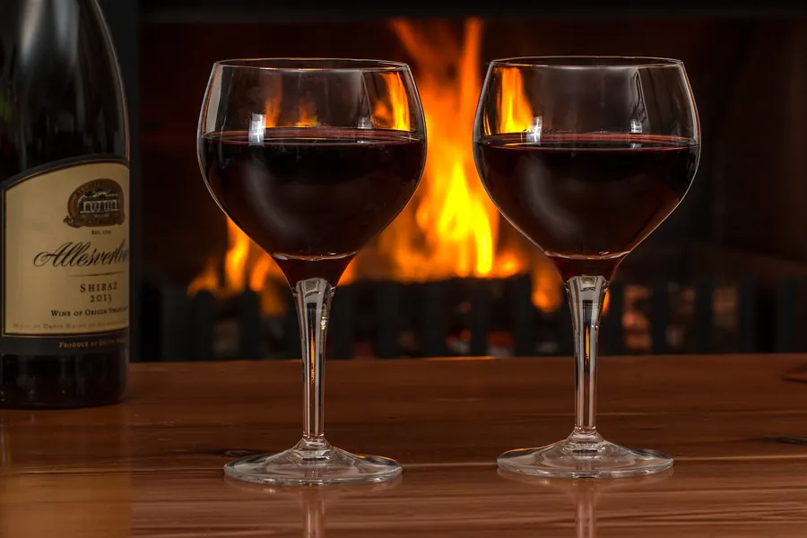 Zwei Gläser Rotwein vor einem Kaminfeuer