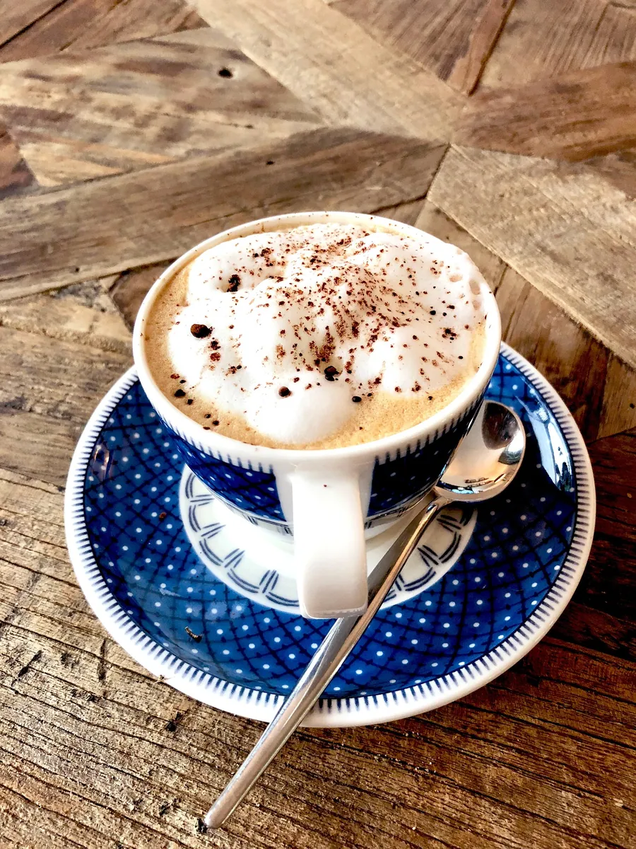 Cappuccino mit Kakaopulver auf einem Holztisch